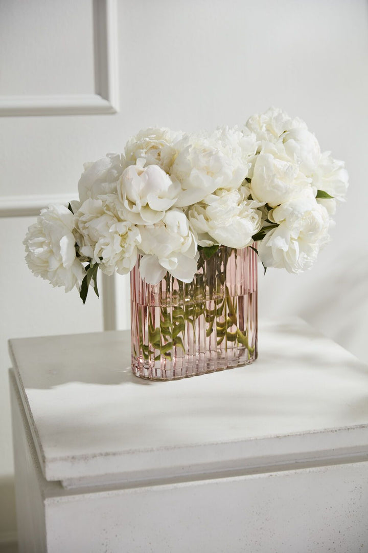 Pink vase with white flowers on a white surface
