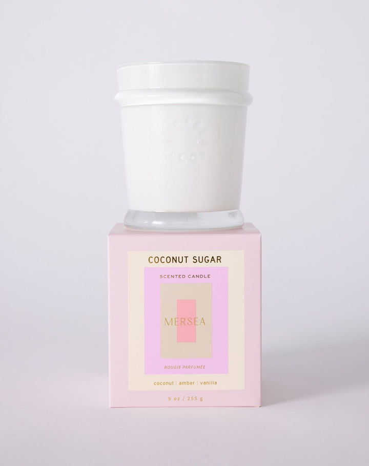 Scented candle labeled 'Coconut Sugar' by Neshea on a light pink background
