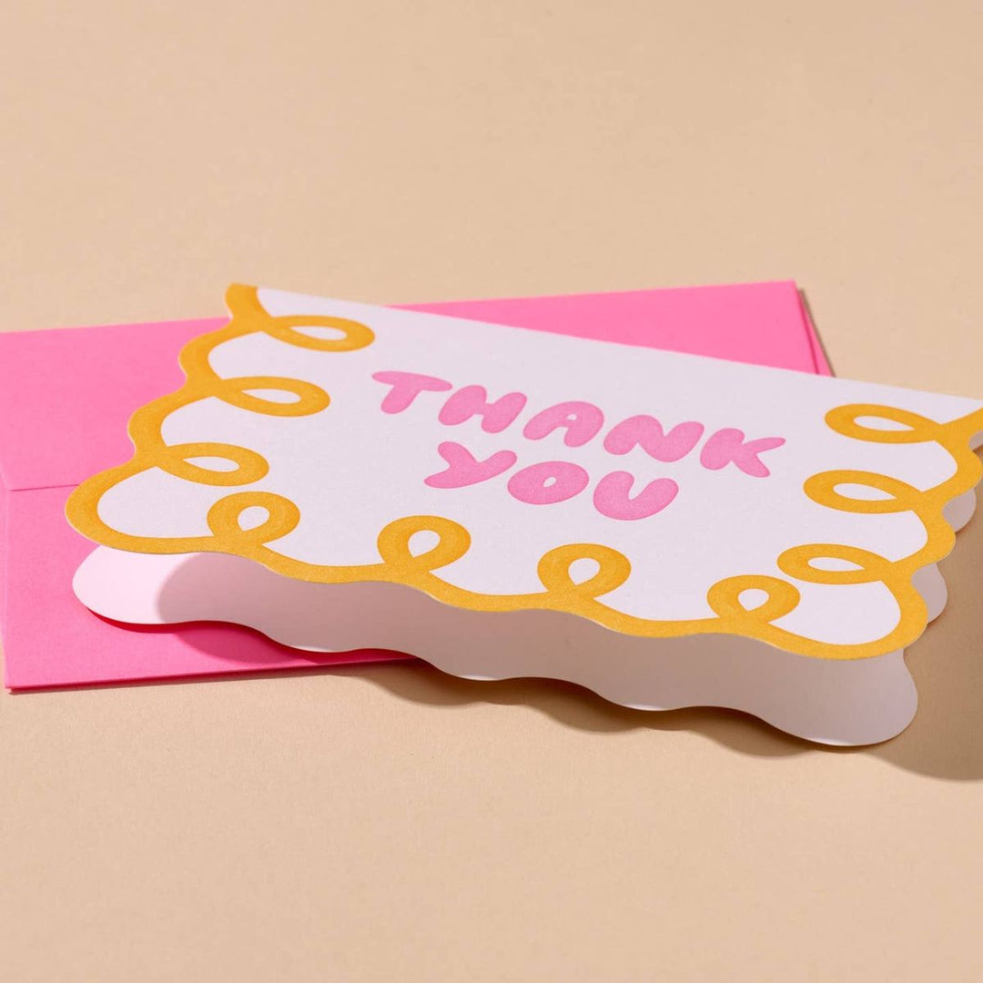 Greeting card with 'THANK YOU' text on a pink envelope against a beige background