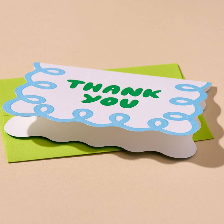 Card with 'Thank You' on a green envelope against a beige background