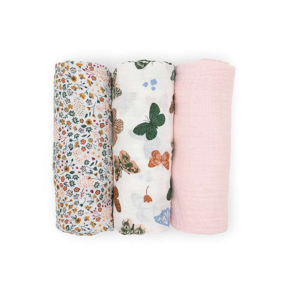 Three swaddle blankets with floral, butterfly, and pink designs on a white background