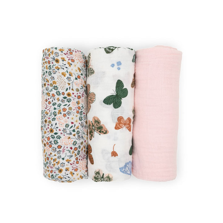 Three swaddle blankets with floral, butterfly, and pink designs on a white background