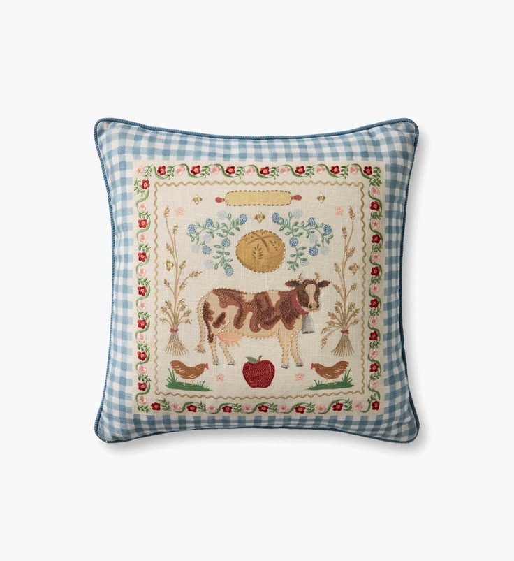 Decorative pillow with a cow and farm-themed embroidery on a blue checkered background