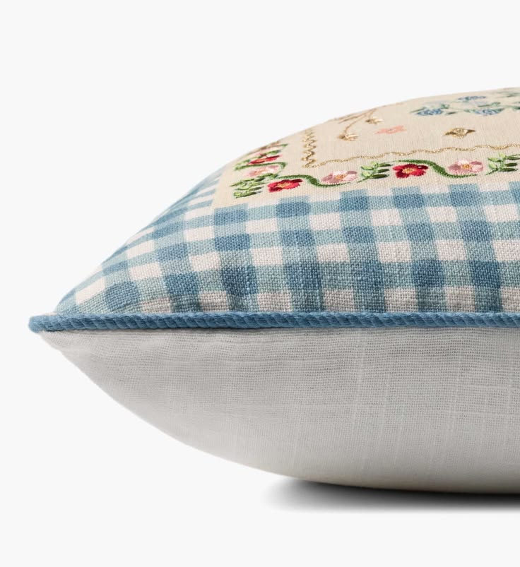 Decorative pillow with blue and white checkered pattern and floral embroidery on a white background