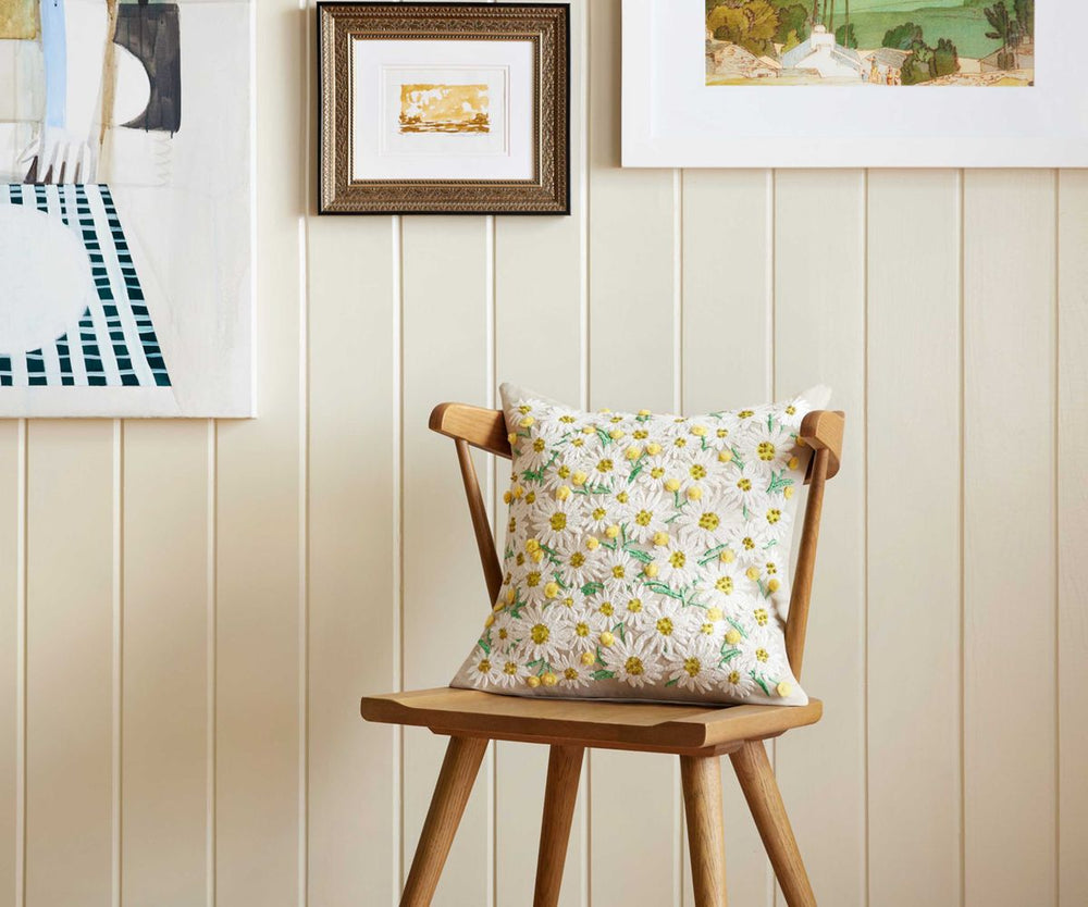 Wooden chair with a floral cushion against a wall with framed pictures