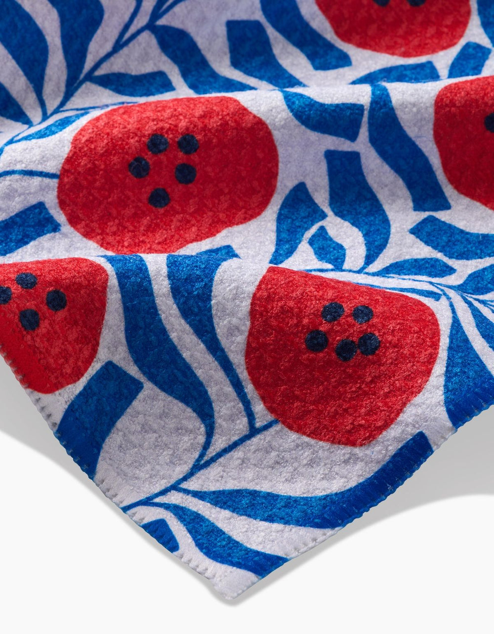Close-up of a fabric with red and blue pattern, featuring red shapes with black dots on a blue and white background.
