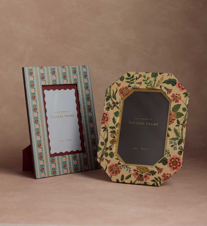 Two decorative picture frames with floral designs on a brown background