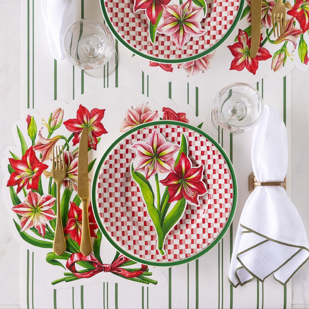 Table setting with floral plates, cutlery, and glasses on a striped tablecloth.