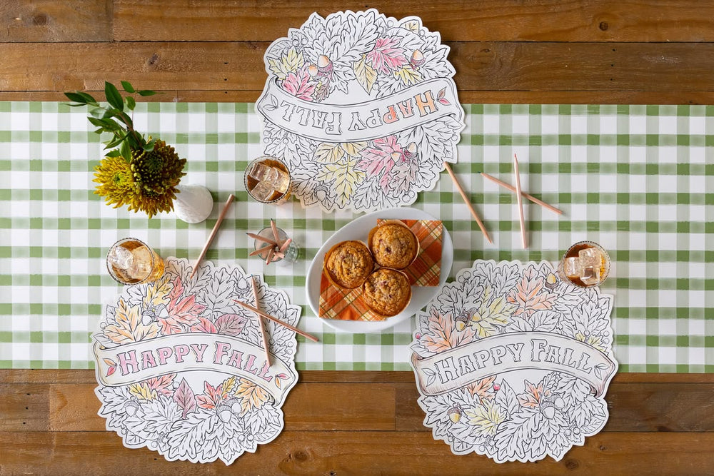Coloring placemats with 'Happy Fall' text on a table setting with muffins and decor.