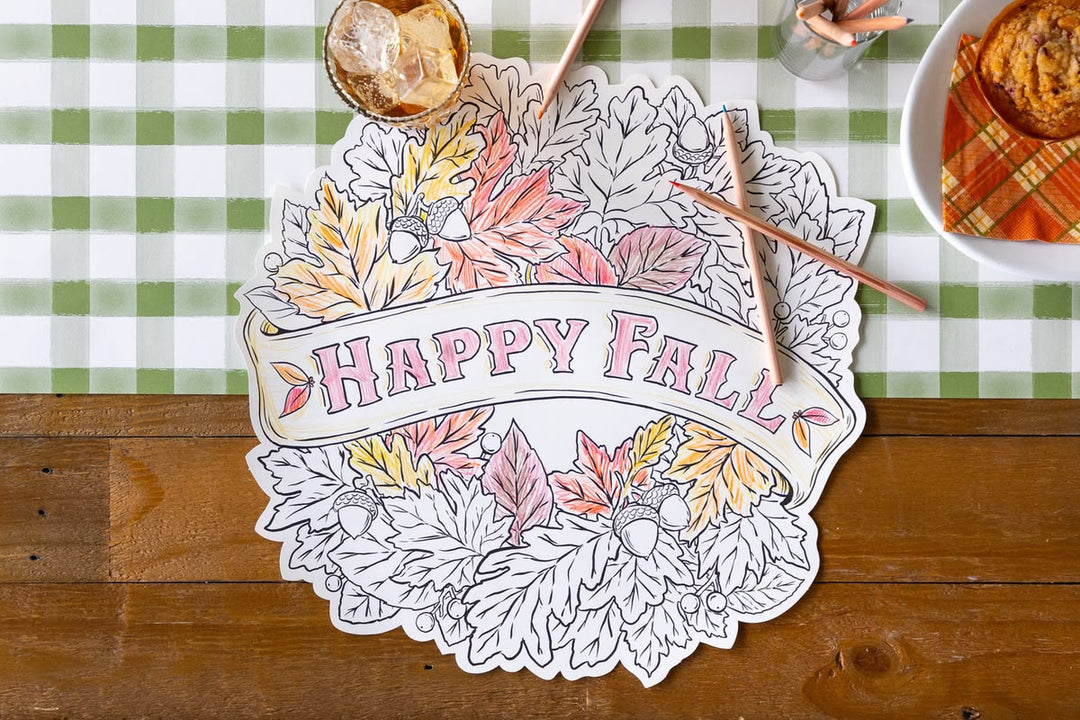 Decorative paper with 'Happy Fall' text on a table with a checkered tablecloth.