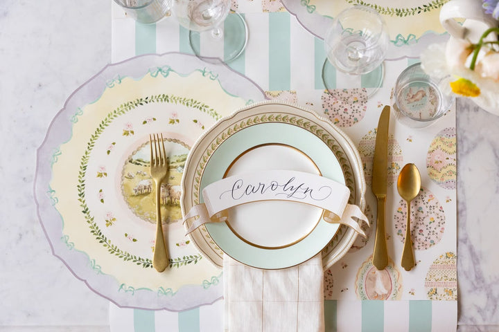 Elegant table setting with gold cutlery, decorative plates, and a striped placemat.