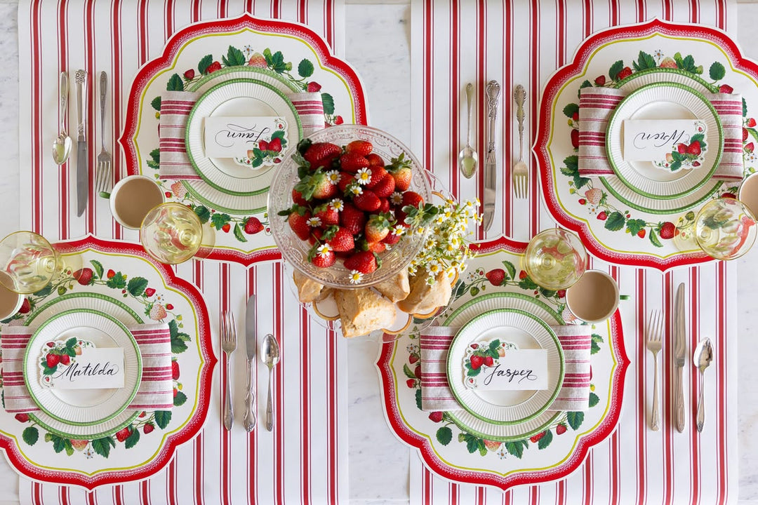 Decorative table setting with patterned plates, cutlery, and a centerpiece on a red and white striped tablecloth.