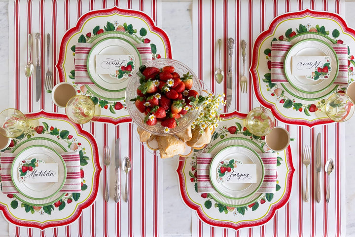 Decorative table setting with patterned plates, cutlery, and a centerpiece on a red and white striped tablecloth.