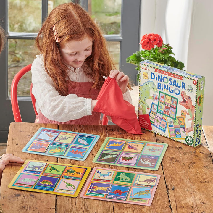 Child playing with a dinosaur-themed bingo game on a wooden table.