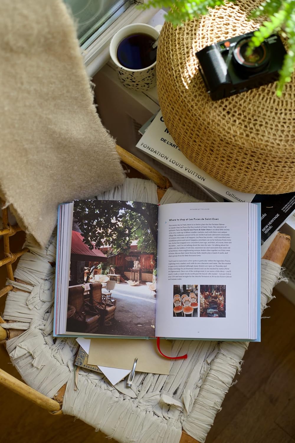 Open book on a textured surface with a cup of coffee and camera in the background