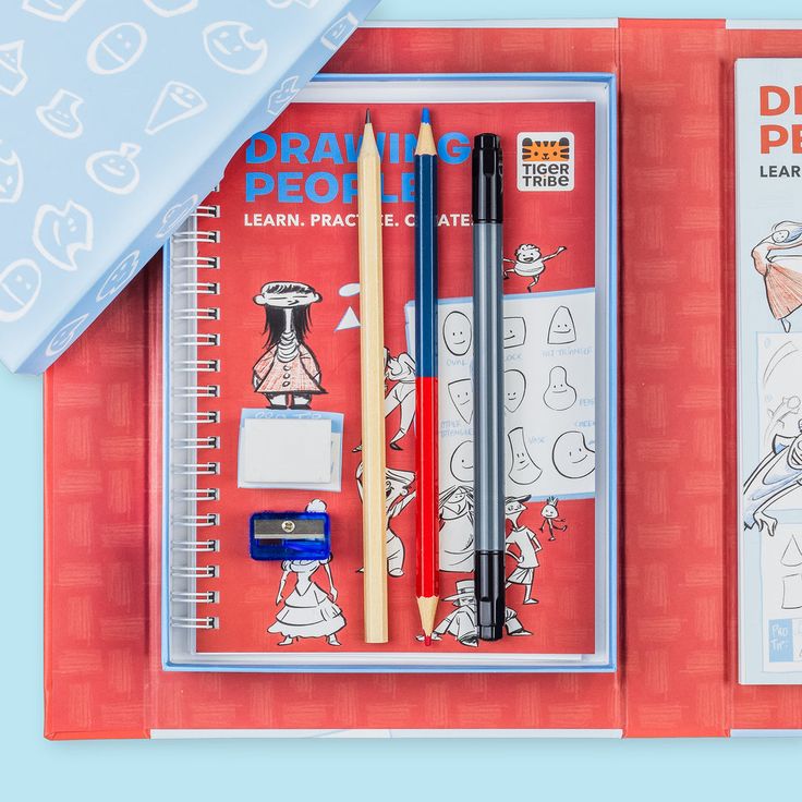Artistic drawing set with notebook, pencils, and eraser on a red background