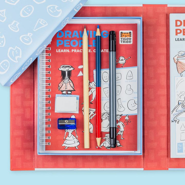 Artistic drawing set with notebook, pencils, and eraser on a red background