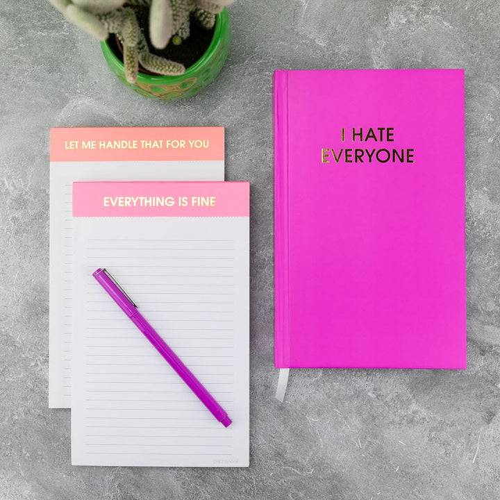 Pink notebook and notepad with motivational phrases on a gray surface.