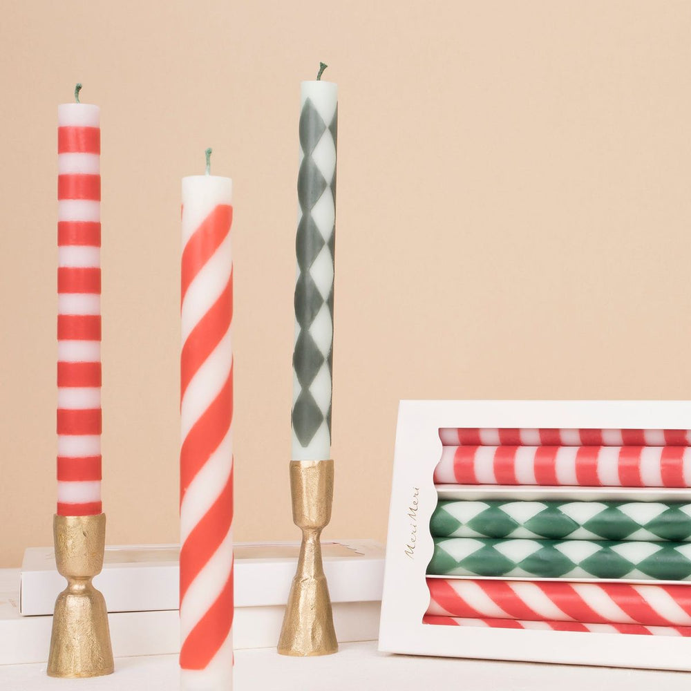Decorative candles with striped and checkered patterns on a beige background