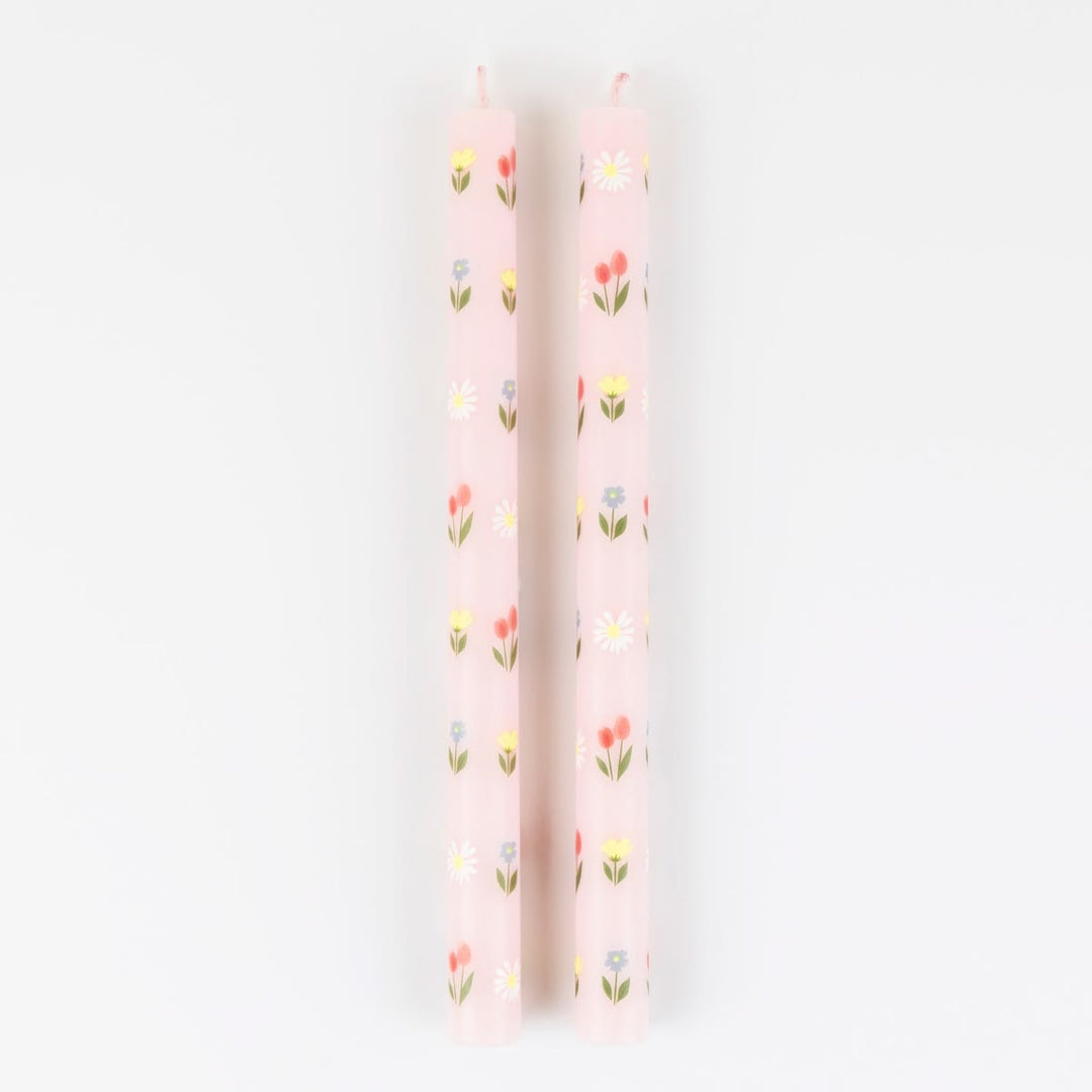 Two pink candles with floral patterns on a white background