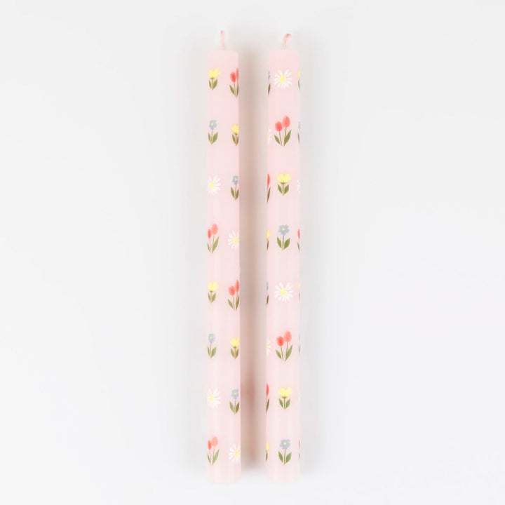Two pink candles with floral patterns on a white background