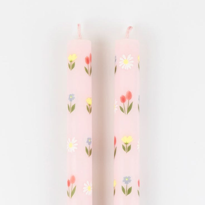 Two pink candles with floral patterns on a light gray background