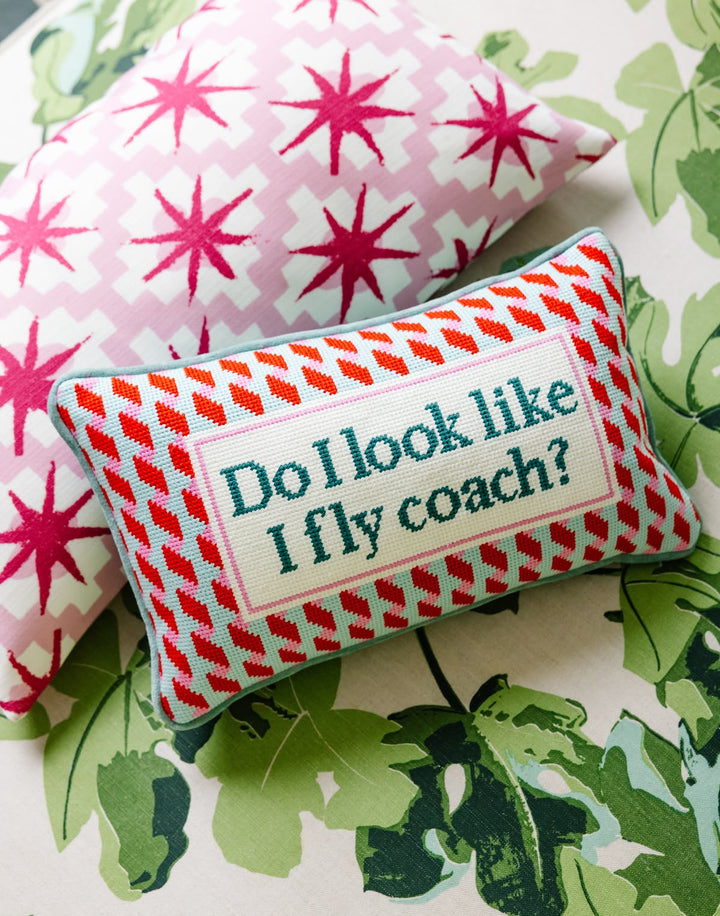Decorative pillow with text 'Do I look like I fly coach?' on a floral background