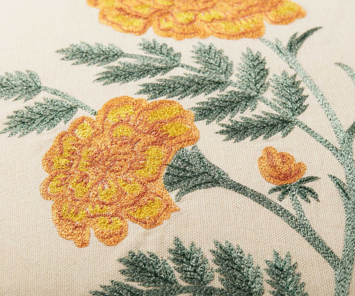 Close-up of embroidered yellow flowers and green leaves on a fabric background
