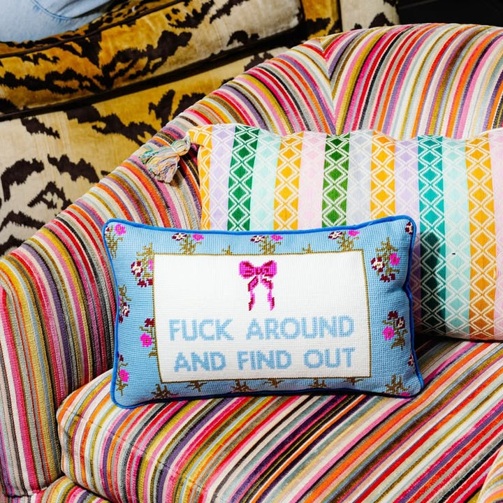 Colorful striped sofa with a decorative pillow featuring text and a bow design.