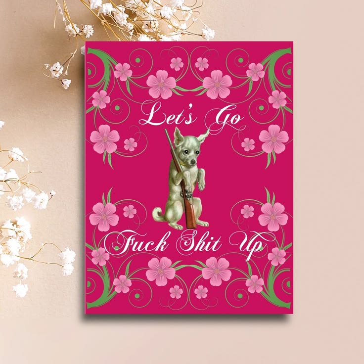 A rectangular pink novelty print or card featuring a small green dog holding a shotgun, surrounded by pink flowers and green swirls, with the text 'Let's Go Fuck Shit Up' in white script. The print is photographed against a beige background with white dried flowers as props.