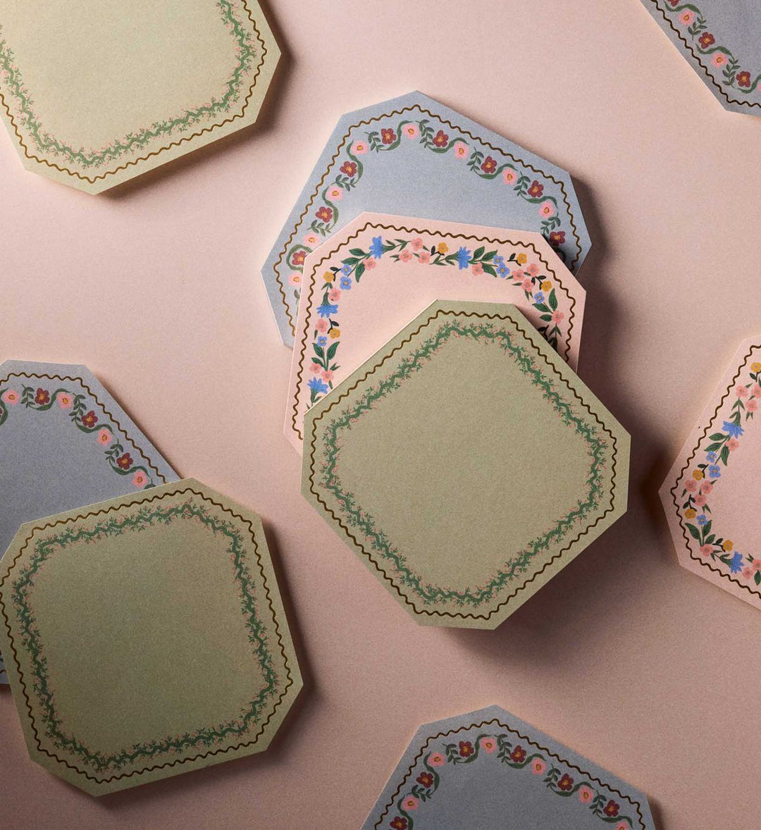 Hexagonal paper coasters with floral patterns on a pink background