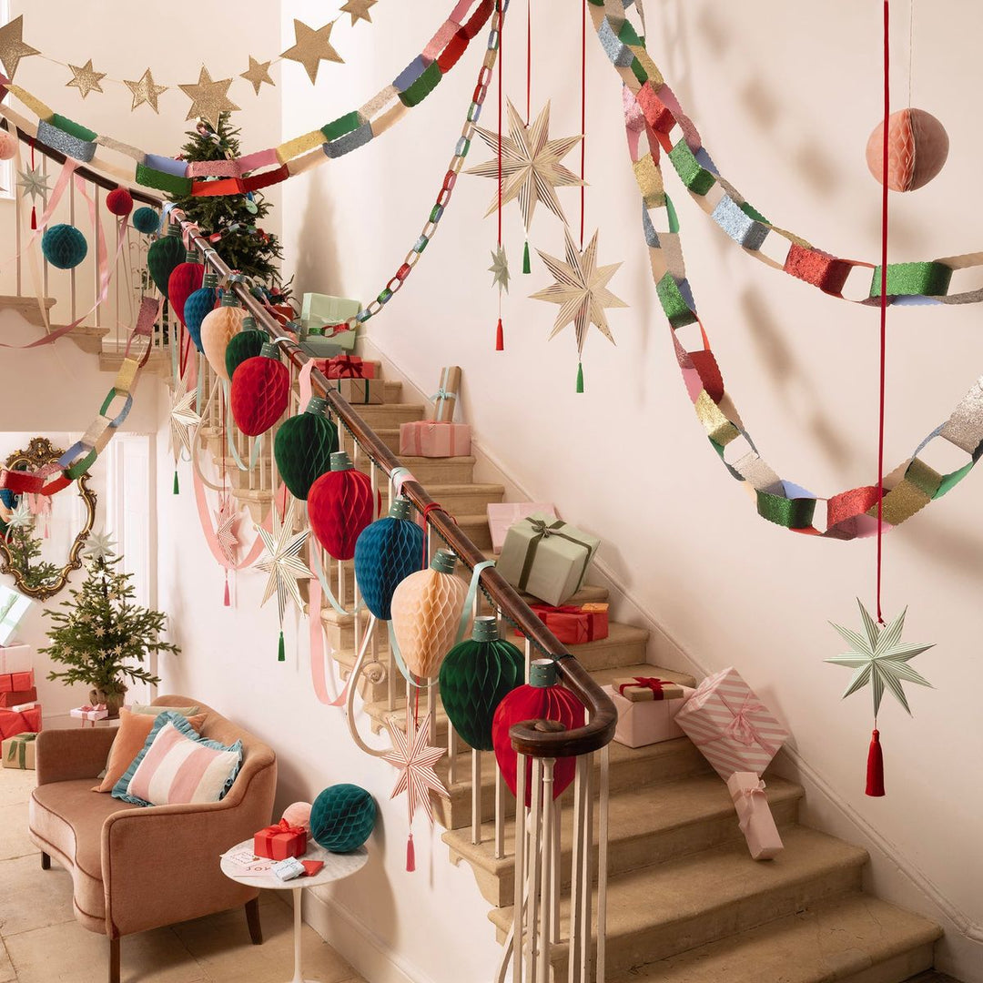 Decorative Christmas staircase with colorful garlands, stars, and gift boxes in a home setting.