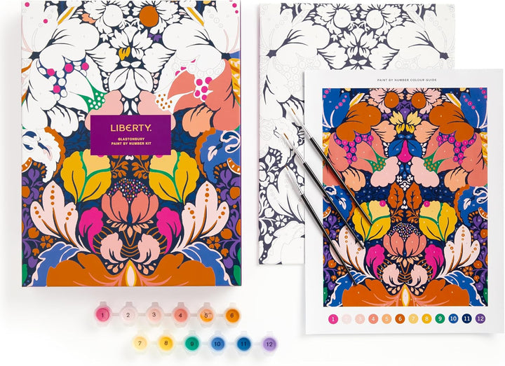 A colorful floral art coloring book set with a matching printed sheet, two paintbrushes, and small numbered paint tubes on a white background. The book cover reads 'LIBERTY' and 'BLAZINGLY COLORFUL ART COLORING BOOK.