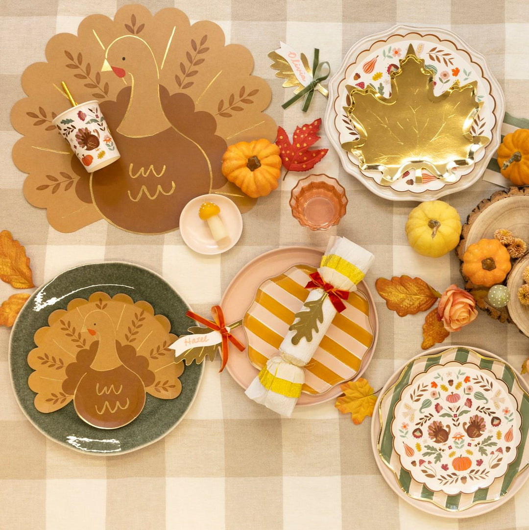 Thanksgiving-themed table setting with decorative plates, pumpkins, and a checkered tablecloth.