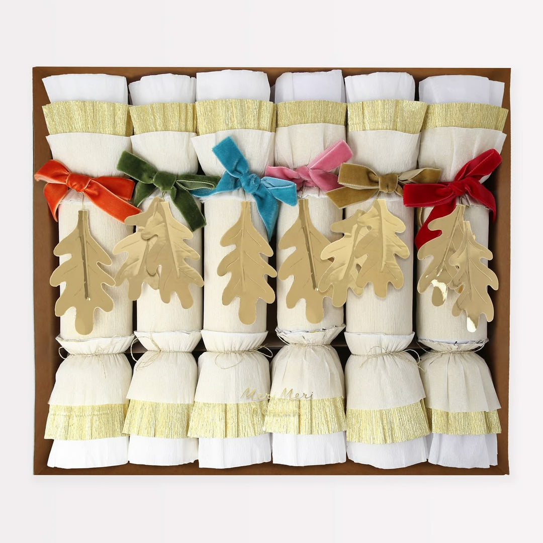 Set of Christmas crackers with colorful ribbons and tree decorations in a box.