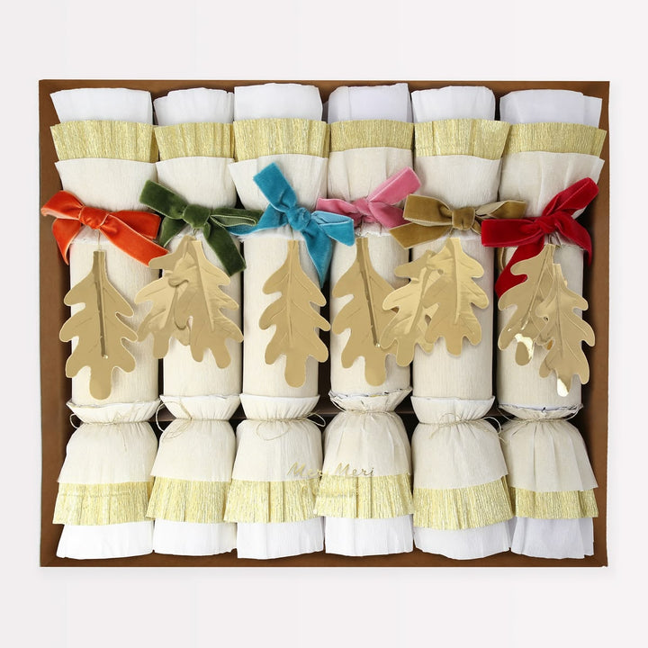 Set of Christmas crackers with colorful ribbons and tree decorations in a box.