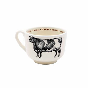 Ceramic mug with cow illustration and text on a white background