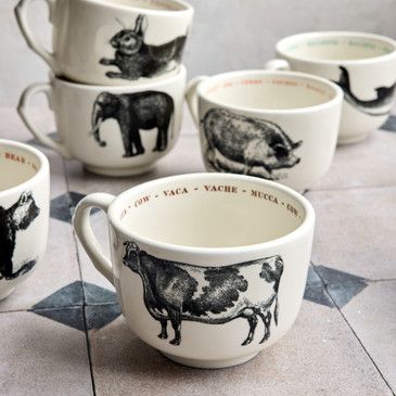 Set of ceramic mugs with animal illustrations on a tiled surface