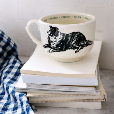Mug with dog illustration on a stack of books next to a plaid cloth