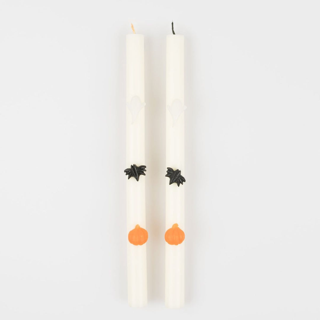 Two white candles with decorative elements on a light gray background