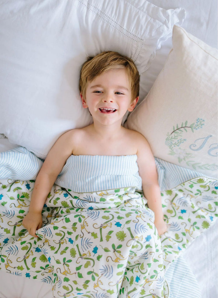 Child lying in bed with monkey-patterned blanket