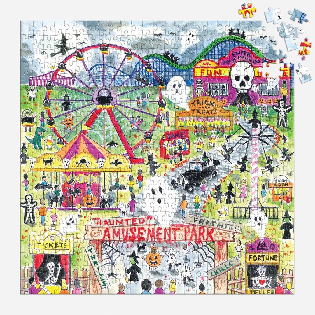 A completed jigsaw puzzle featuring a whimsical Halloween amusement park scene with a ferris wheel, carnival tents, ghosts, skeletons, haunted-house signs, and playful illustrations. Several loose puzzle pieces are scattered around the edges on a white background.
