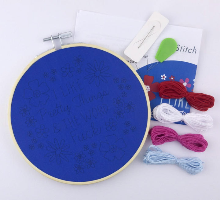 Embroidery hoop with blue fabric and embroidery thread on a white background