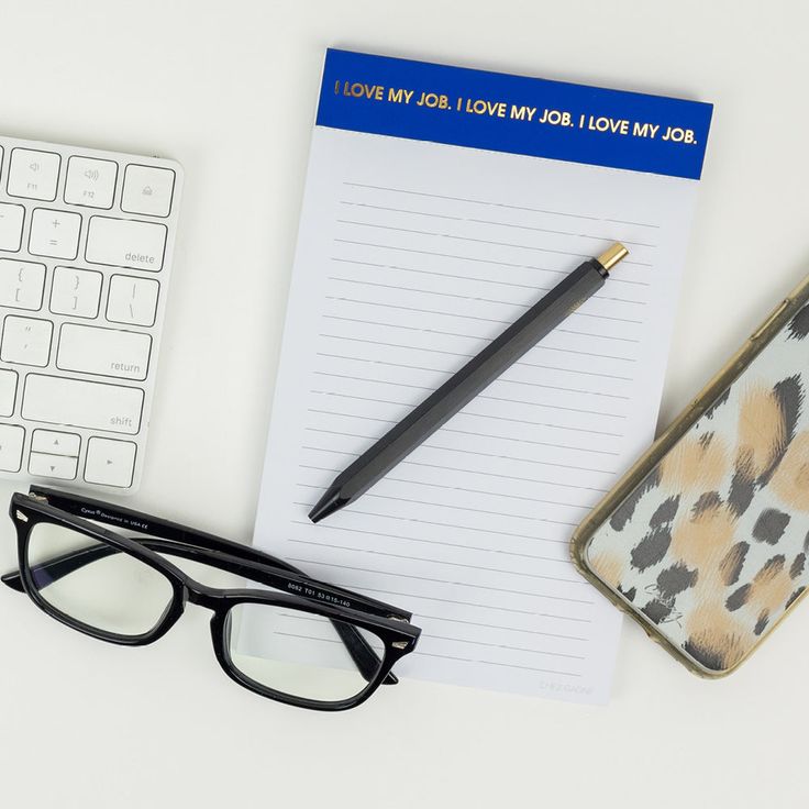 Notepad with 'I LOVE MY JOB.' text, pen, glasses, and phone on a desk.