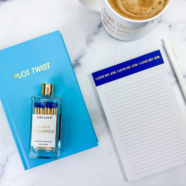 Notebook, matches, and notepad on a marble surface with coffee.