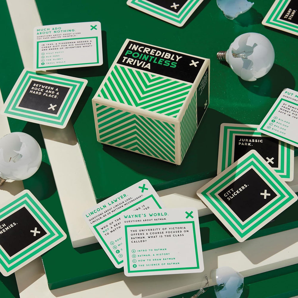 Hexagonal box labeled 'Incredibly Pointless Trivia' surrounded by green and black cards on a green surface.