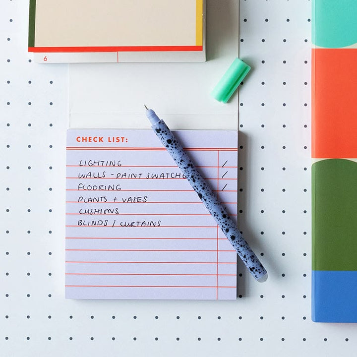 Notepad with a check list and pen on a pegboard background