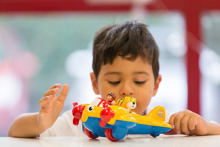 Child playing with a toy airplane at a table