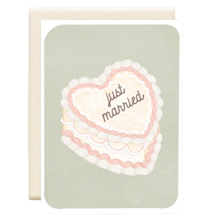 A square greeting card with a white envelope behind it, featuring a heart-shaped frosted cake illustration with the words 'just married' on a pale sage green background.