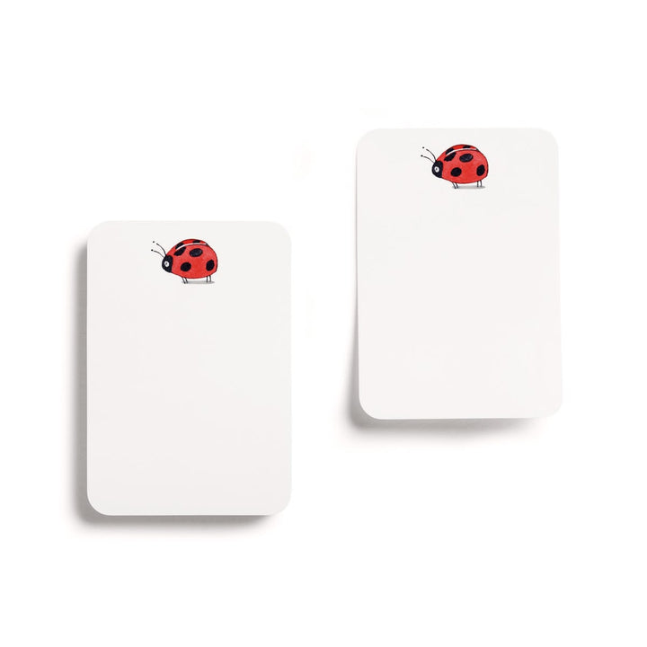 Two white notepads with red ladybug designs on a white background